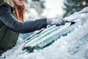 woman scraping ice off car's windshield