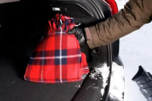 the driver placing a warm windproof blanket in car trunk