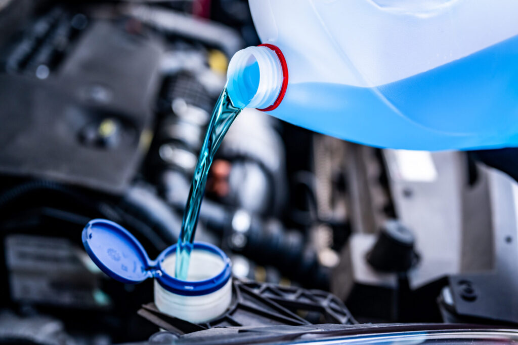 Pouring antifreeze. Filling a windshield washer tank with an antifreeze in winter cold weather.